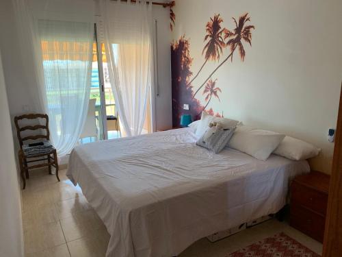 een slaapkamer met een wit bed met een palmboom aan de muur bij La azotea in Cambrils