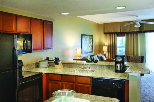 a kitchen with wooden cabinets and a black refrigerator at Club Wyndham Cypress Palms in Kissimmee