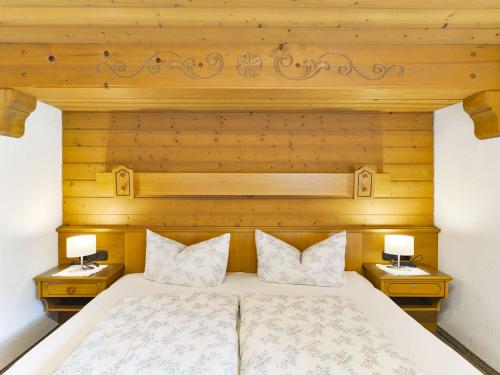 a bedroom with a wooden headboard and two night stands with lamps at Haus Oberhauser in Schoppernau