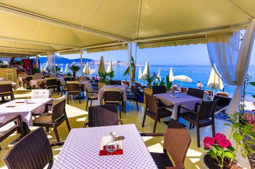 a restaurant with tables and chairs with a view of the ocean at Apartments Kuce Lekovica Beach & snack bar- Bistro in Bar