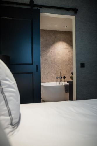 a bedroom with a bed and a tub in a bathroom at Boutiquehotel 't Fraeyhuis - adults only in Bruges