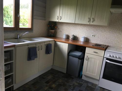 une cuisine avec des armoires blanches et un évier dans l'établissement Le chalet des Cambuses, à Saint-Dié-des-Vosges