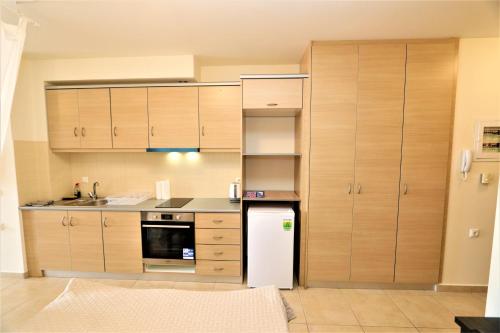 a kitchen with wooden cabinets and a white refrigerator at Dolphins Apartments in Loutra Edipsou