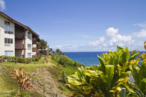 a building on a hill with the ocean in the background at Club Wyndham Shearwater in Princeville