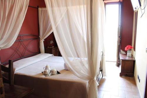1 dormitorio con cama con dosel y cortinas blancas en IL Ciliegio Dell 'Etna, en Giarre