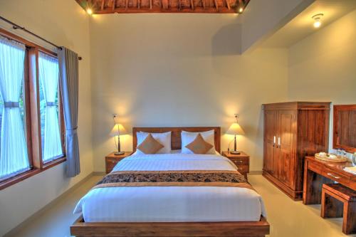 a bedroom with a large bed and two windows at Arya Resort Nusa Penida in Nusa Penida