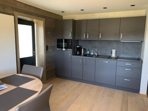 une cuisine avec des placards gris et une table avec des chaises dans l'établissement GITES SAINT ROMARY, à Saint-Étienne-lès-Remiremont