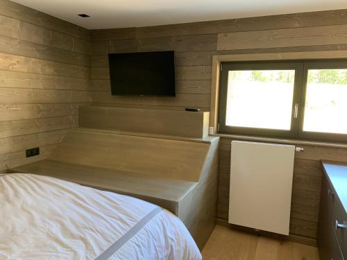Un dormitorio con una cama y un televisor de pantalla plana. en GITES SAINT ROMARY, en Saint-Étienne-lès-Remiremont