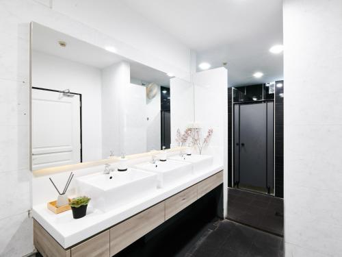 a white bathroom with two sinks and a mirror at BEAT. Sports Hostel in Singapore