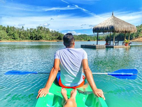 a man sitting on a paddle board in the water at Levit Glamping - Hotel Guatapé ADULTS ONLY in Guatapé