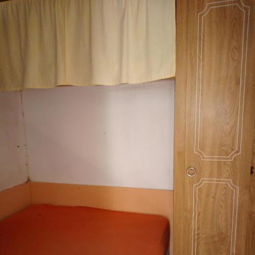 Cette chambre dispose d'une fenêtre avec un matelas rouge et un rideau. dans l'établissement Le Havre de Paix Mobil home ancien, à Pordic