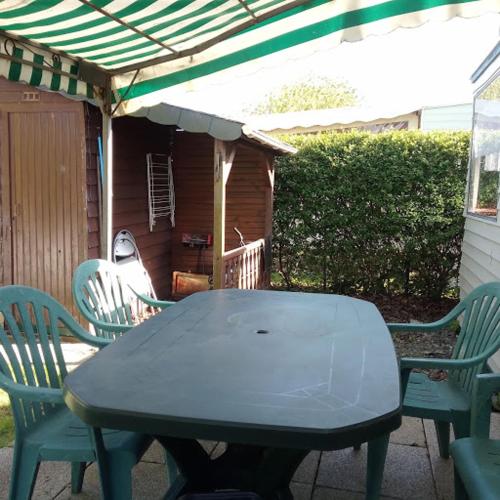 - une table et des chaises sur une terrasse avec un parasol dans l'établissement Le Havre de Paix Mobil home ancien, à Pordic