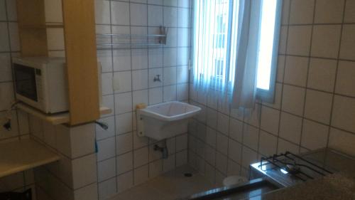 a small bathroom with a sink and a microwave at Apart Hotel Quartier Latin in Vitória