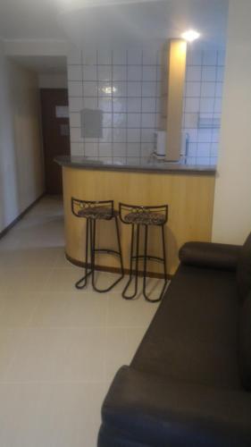 a kitchen with a counter and two stools in a room at Apart Hotel Quartier Latin in Vitória