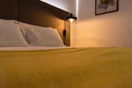 a bedroom with a bed with white pillows and a lamp at O Paço - exclusive accommodation in Tomar