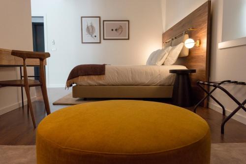 a bedroom with a bed and a yellow ottoman at O Paço - exclusive accommodation in Tomar