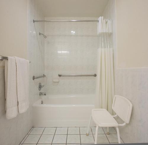 ein weißes Bad mit einer Dusche und einem weißen Stuhl in der Unterkunft Regency Inn at San Francisco Airport in San Bruno