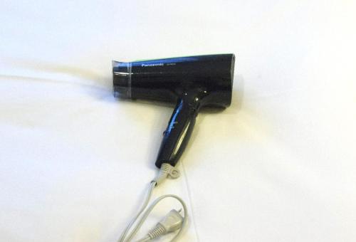 a black hair dryer with a pair of scissors at Tokyo Plaza Hotel in Tokyo