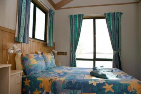 1 dormitorio con cama y ventana en Tuross Lakeside Holiday Park, en Tuross Heads