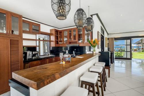 a kitchen with a large wooden counter and chairs at BougainVilla - Oceanfront villa with Cook, ideal for Weddings and Events in Keramas