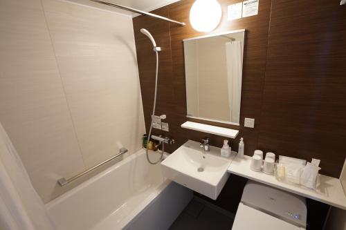 a bathroom with a sink and a toilet and a bath tub at Hotel Quest Shimizu in Shizuoka