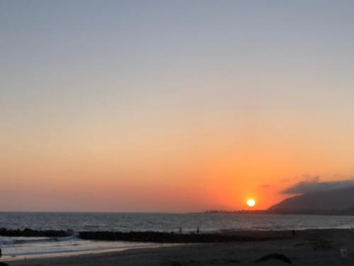 a sunset on the beach with the sun in the sky at The Shores Inn in Ventura