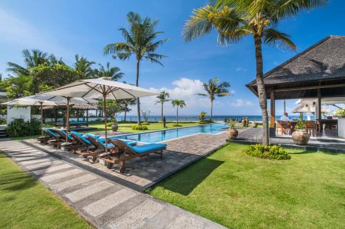 a resort with a swimming pool and palm trees at BougainVilla - Oceanfront villa with Cook, ideal for Weddings and Events in Keramas