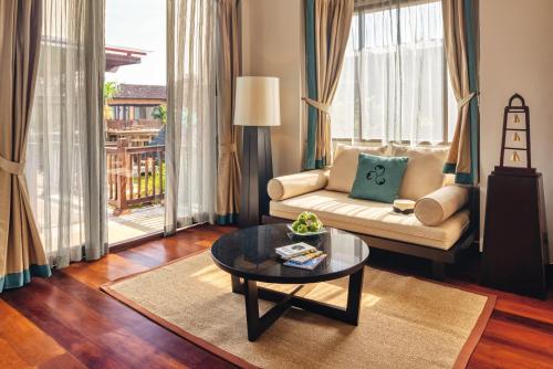 a living room with a couch and a table at Mövenpick Asara Resort & Spa Hua Hin in Hua Hin