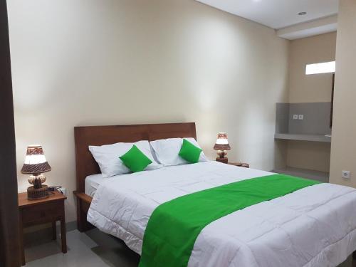 ein Schlafzimmer mit einem grünen und weißen Bett mit zwei Lampen in der Unterkunft Gusti Room in Ubud