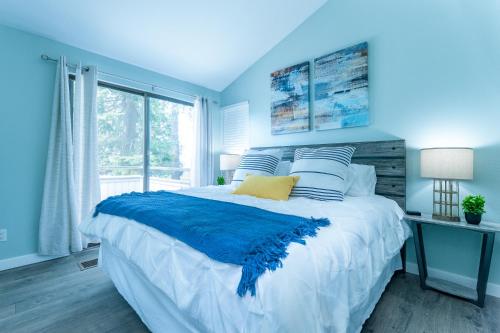 Un dormitorio azul con una cama grande y una ventana en Birch Bay waterfront condo - Lofted layout & steps from beach, en Blaine