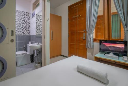 a bathroom with a bed and a sink and a toilet at LeGreen Suite Tebet in Jakarta