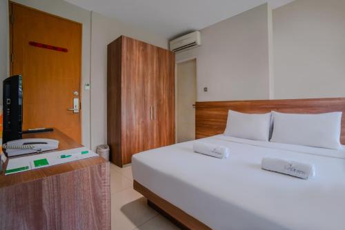 a bedroom with a white bed and a television at LeGreen Suite Tebet in Jakarta