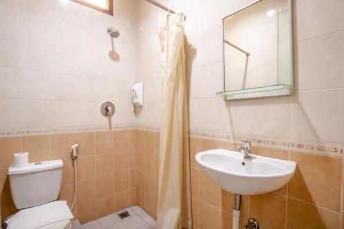 uma casa de banho com um lavatório, um WC e um espelho. em LeGreen Suite Setiabudi em Jakarta