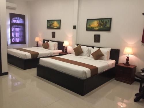 two beds in a hotel room with two lamps at Private Boutique Home with Pool, The Fin Angkor Boutique in Siem Reap
