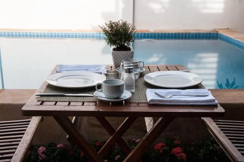 a wooden table with plates and a coffee cup on it at Private Boutique Home with Pool, The Fin Angkor Boutique in Siem Reap