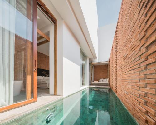 an indoor swimming pool in a house with a brick wall at Sala Ayutthaya in Phra Nakhon Si Ayutthaya