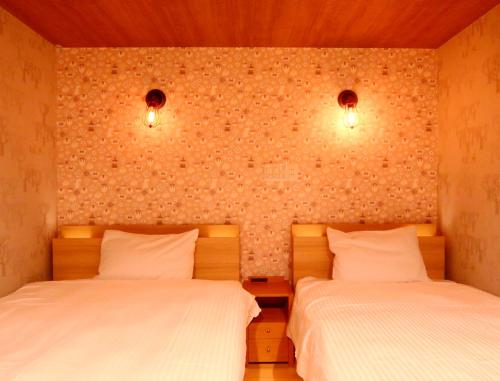 a bedroom with two beds and two lights on the wall at Amagiso in Kawazu