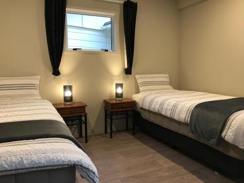 two beds in a room with a window and two lamps at Angie's Rural Retreat in Wainuiomata