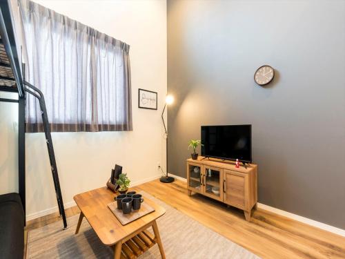 Una sala de estar con un televisor y una mesa. en TRIP POD CHIYO A, en Fukuoka
