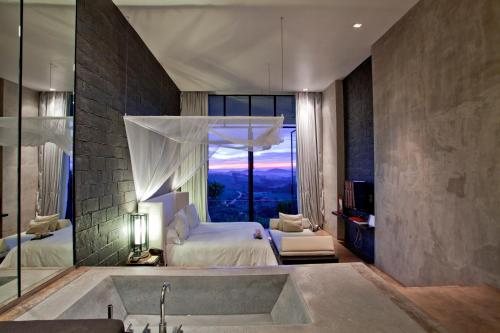 a bedroom with a bed and a tub and a window at Sala Khaoyai in Wangkata