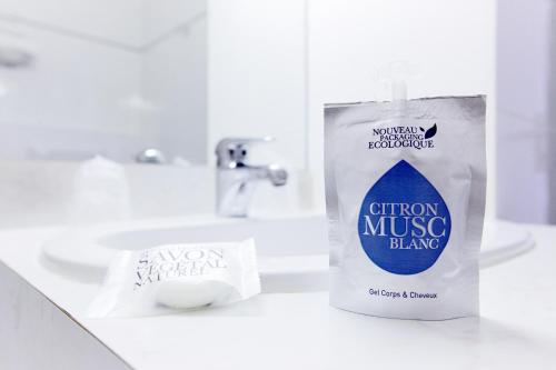 a container of cotton music bling sitting on a bathroom sink at Hôtel Restaurant Kyriad Mulhouse Nord Illzach in Illzach