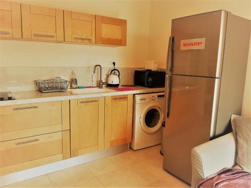 een keuken met een roestvrijstalen koelkast en een wasmachine bij Charming beach 2 room flat in Haifa