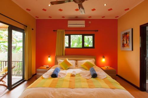 a bedroom with orange walls and a bed with shoes on it at Casa De Leela Self Catering Guest House in La Digue