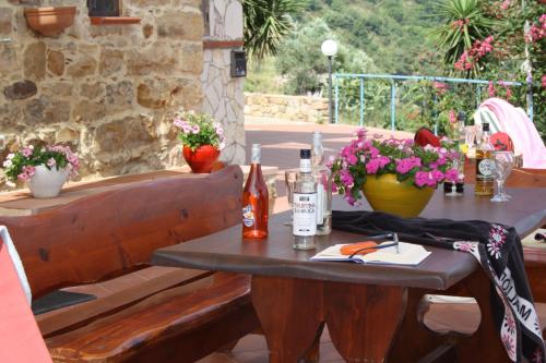 a table with bottles and flowers on a patio at Camere & Case Vacanze Lo Scoglio in Castel di Tusa