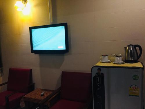 a flat screen tv on a wall above a refrigerator at Nett Hotel in Lop Buri