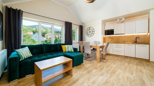 ein Wohnzimmer mit einer grünen Couch und einer Küche in der Unterkunft Apartamenty EverySky - Emilii Plater 18-18A in Karpacz
