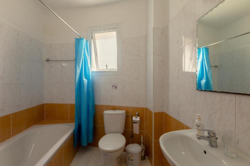a bathroom with a toilet and a tub and a sink at Oceania Bay Village in Pyla