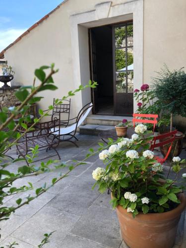 a patio with two chairs and flowers in pots at Le Colombier in Sablet