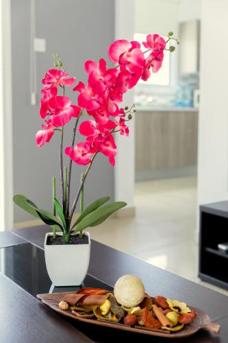a plate of food and a vase with pink flowers at Oceania Bay Village in Pyla