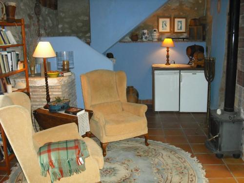 a living room with two chairs and a stove at Casa Gallinera in Benissiva